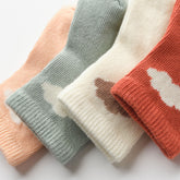 Close-up of cotton baby socks with minimal cloud design and soft color palette